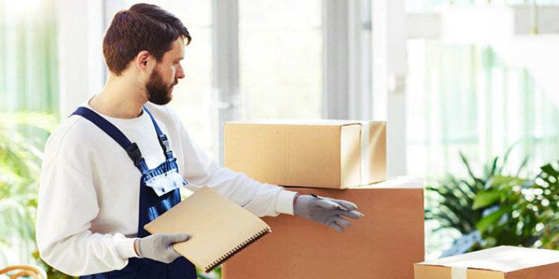 young bearded man in uniform checking the packed boxes