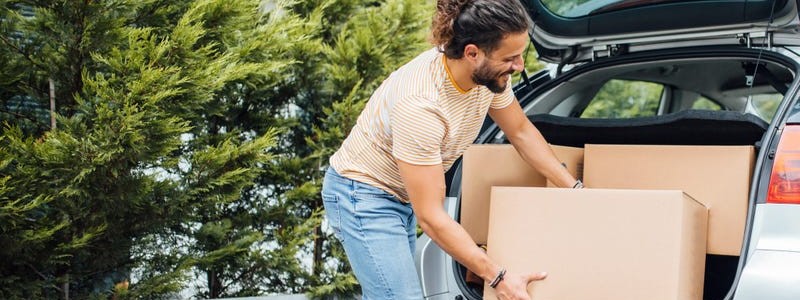young man packing cardboard boxes into a car