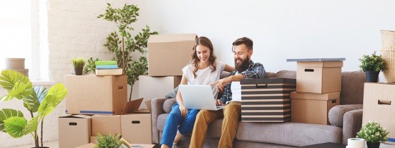 young couple sitting on a couch and searching for something on the internet