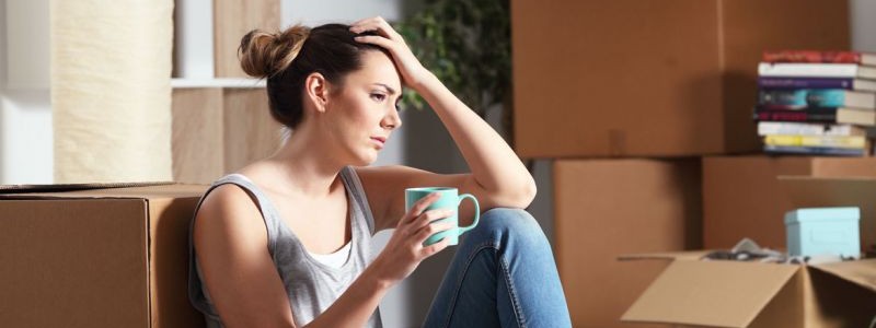 young woman sitting on the floor with a coffee mug looking stressed