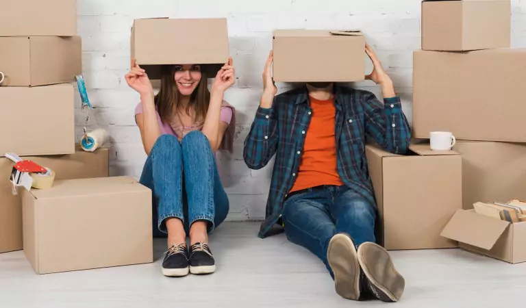 couple putting boxes on their heads and sitting on the floor