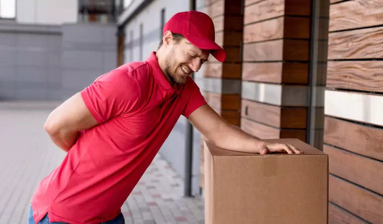 young man looking in pain standing with some cardboard boxes